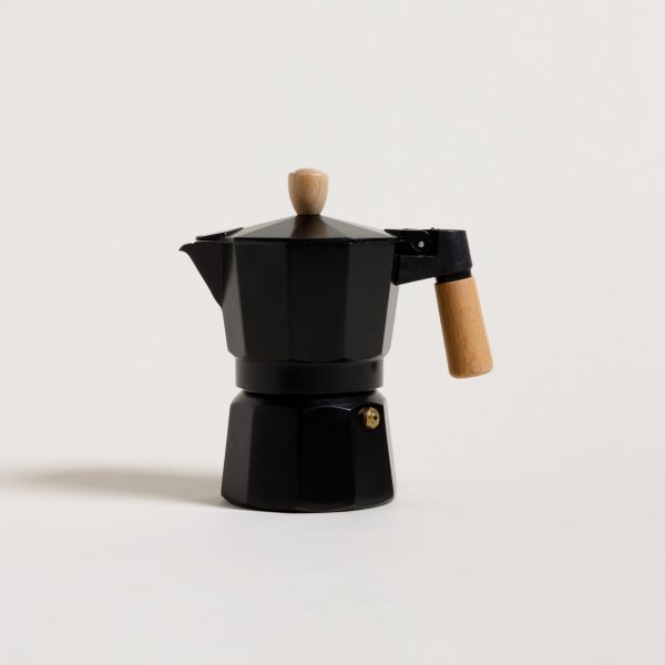 Una cafetera con filtro y un filtro de café sobre una mesa de madera.